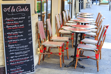 Street cafe in Paris - traditional wicker furniture and menu board exposed on the pavement, Paris,...