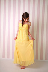 Fashion young woman in long yellow dress, studio