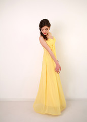 Fototapeta na wymiar Fashion young woman in long yellow dress, studio on white