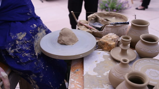 Pottery maker uses a kick wheel to hand mold a pot from clay 