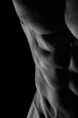 Low key photo of an athletic man with perfect abs