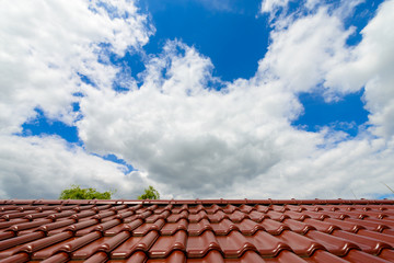 Close-up of glazed brown roof tiles against blue cloudy sky background
