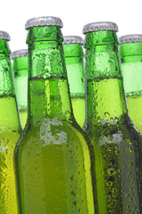 Closeup Group of Backlit Green Beer Bottles with condensation over a white background vertical format