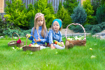 Two little girls with baskets full of harvest of tomatoes 