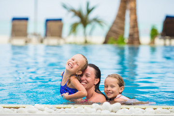 Fototapeta na wymiar Mother and two kids enjoying summer vacation in luxury swimming