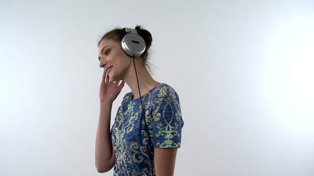 A head and shoulders shot of a Girl with headphones and moving and dancing with the music