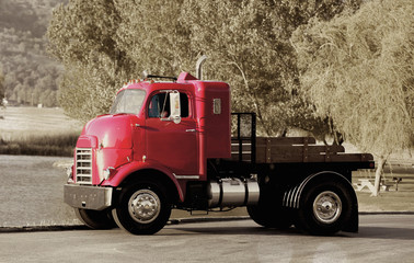 An old red vintage freight truck in a sepia toned background.