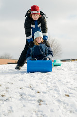 two kids sledding in winter
