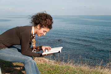 lady reading a book near the sea