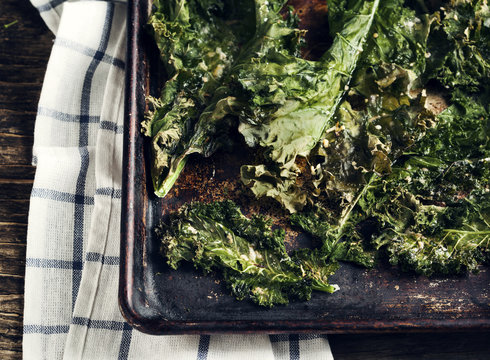 Crispy cheese and chili kale chips on baking tray. Toned image