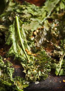 Crispy cheese and chili kale chips on baking tray. Selective foc