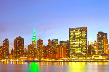 New York City, Manhattan famous landmark buildings skyline in downtown at beautiful colorful sunset with reflections