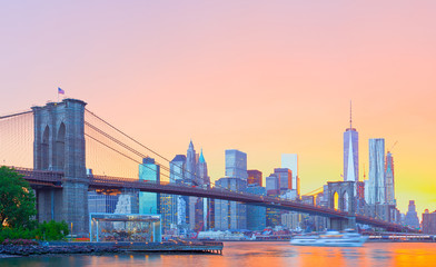 New York City, Manhattan downtown panorama with famous landmark Brooklyn Bridge at colorful sunset