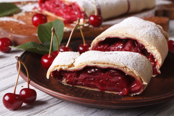 Sliced strudel with cherry close-up on a plate. horizontal
