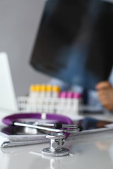 Doctor's stethoscope with folder and bottle of pills on the desk