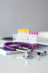 Doctor's stethoscope with folder and bottle of pills on the desk