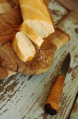 White loaf and knife on a wooden chopping board on a brown cloth in a cage