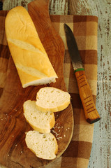 White loaf and knife on a wooden chopping board on a brown cloth in a cage