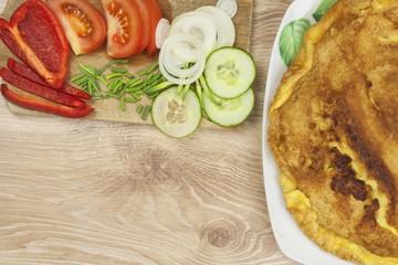 Scrambled egg omelet with vegetables on a wooden table. Preparation of fast food home.
