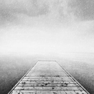 Fototapeta Wooden jetty, pier on deep cold sea, ocean. Raining sky
