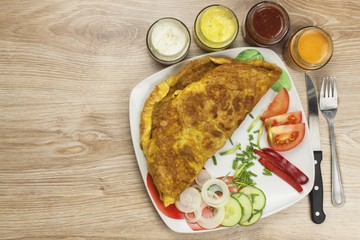 Scrambled egg omelet with vegetables on a wooden table. Preparation of fast food home.
