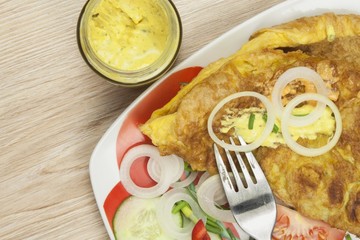 Scrambled egg omelet with vegetables on a wooden table. Preparation of fast food home.

