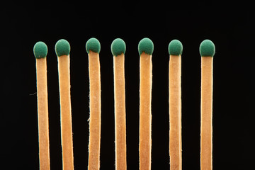 Set of seven green wooden matches isolated on black background