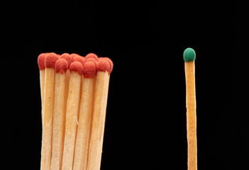 Group of red wooden matches standing with green match