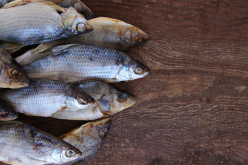 Salty dry river fish on a brown wooden background.