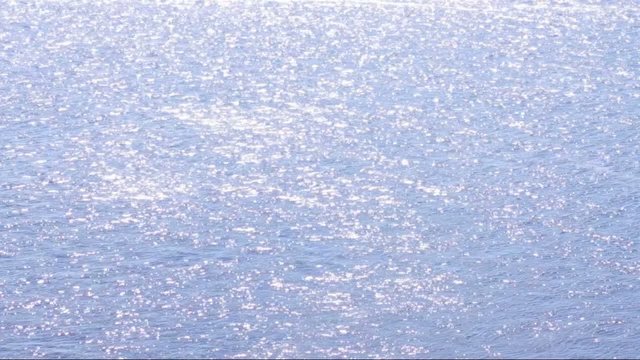 Sun shines on the water surface of the sea, lake, river or ocean