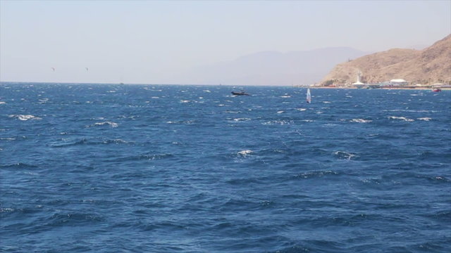 The Gulf of Eilat - Windsurfing and boats sailing in the Red Sea.
Eilat's Underwater Observatory appears on the horizon.
