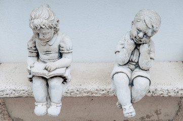 sculpture of a boy and a girl sitting on the bench