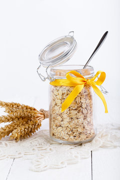 The oat flakes in glass jar and wheat.
