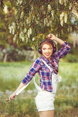 Hipster girl with headphones dancing on the street.