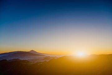 Sun over mountains on blue sky