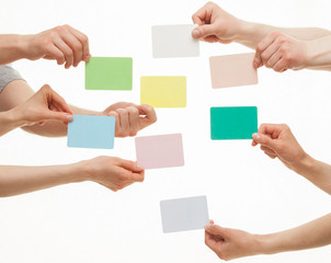 Many hands holding colorful paper cards
