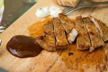 Cut pork steak and bbq dip on chopping board