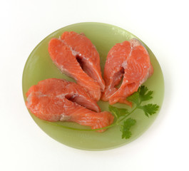 Three salmon steaks are  on a plate
