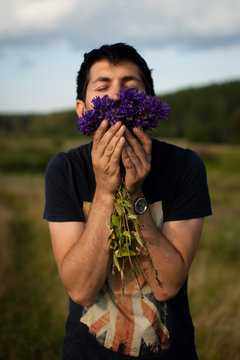 Man Smelling Flowers In A Field