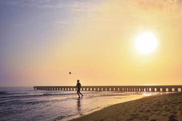 Footballer is playing on the morning Beach