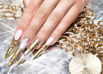Beautiful long nails in a gold design with rhinestones. Nail art