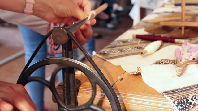 Woman using an antique winder for wrapping yarn onto a spool