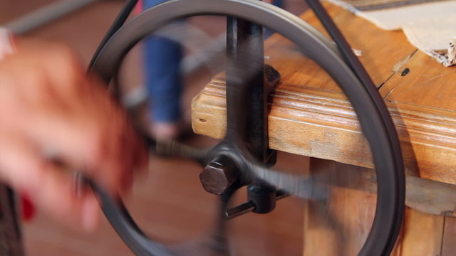 Woman using an antique winder for wrapping yarn onto a spool