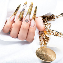 Beautiful long nails in a gold design with rhinestones. Nail art