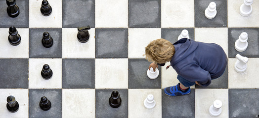 Child playuing outdoor chess