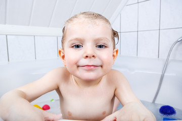 Adorable toddler boy having fun in bathtub