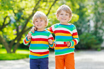Two little kid boys in colorful clothing walking hand in hand