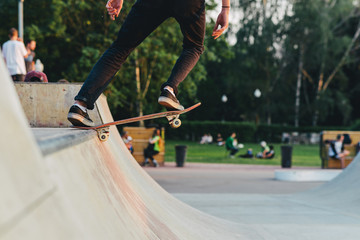 skateboarder at skate park on the ramp to perform tricks on the board in the light of the setting sun. soft focus and beautiful bokeh in the background. - obrazy, fototapety, plakaty