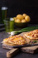 Flammkuchen mit Kartoffeln auf Holzbrett