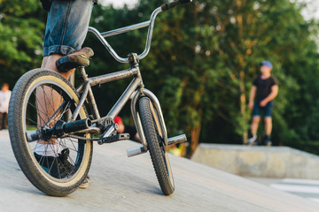 BMX rider on a bike is ready to perform a trick on a ramp in the summer skatepark. soft focus and...